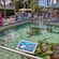 People looking into an outdoor water tank with a coral reef and sharks